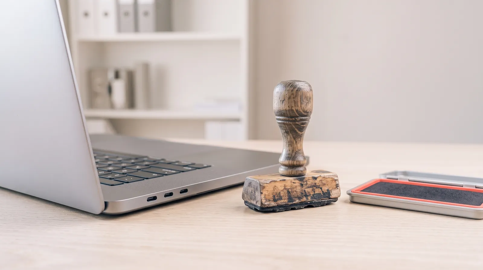 Un tampon administratif en bois posé à côté d'un clavier d'ordinateur portable, dans le noir, éclairé par une seule lumière corail